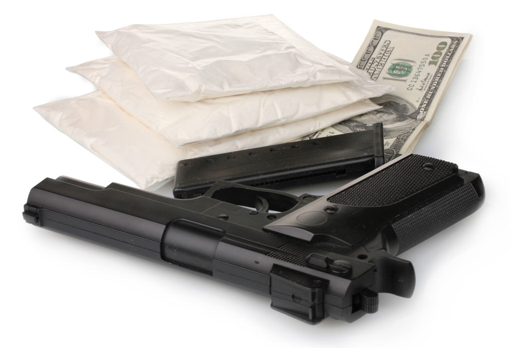 Cocaine in packet with gun and money isolated on white
